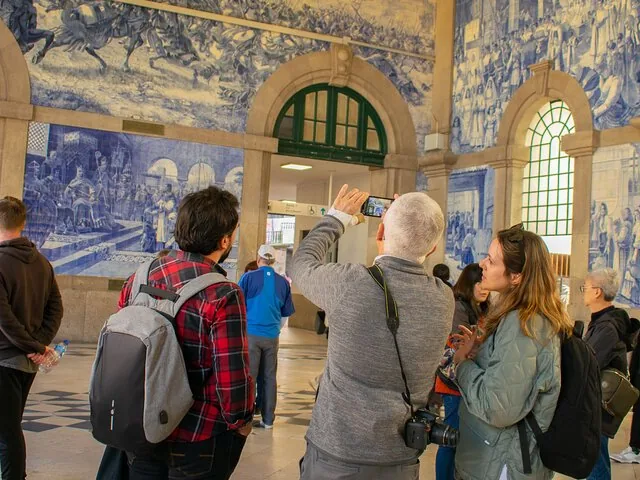 Gruppo di turisti scatta foto ai grandi murales di azulejos blu alla stazione di São Bento