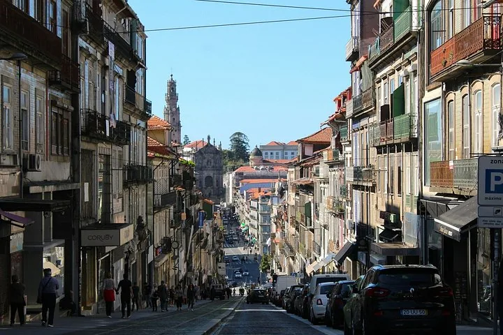 Eine belebte, enge Straße in Porto mit historischen Gebäuden auf beiden Seiten