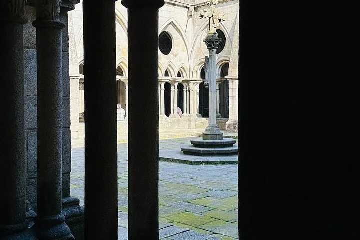 Ein steinerner Innenhof, gesehen durch die dunklen Säulen eines Kreuzgangs