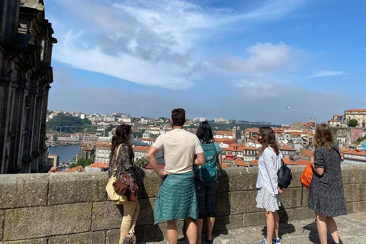 Un gruppo di persone si gode la vista panoramica della città da un balcone in pietra